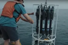 Screenshot from video with researchers on a ship collecting water. 