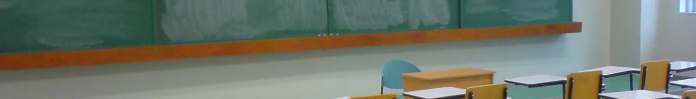 An empty classroom with chairs and a blackboard.